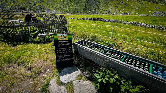 Holzrinne mit Getränkekisten, durchflossen von Bachwasser